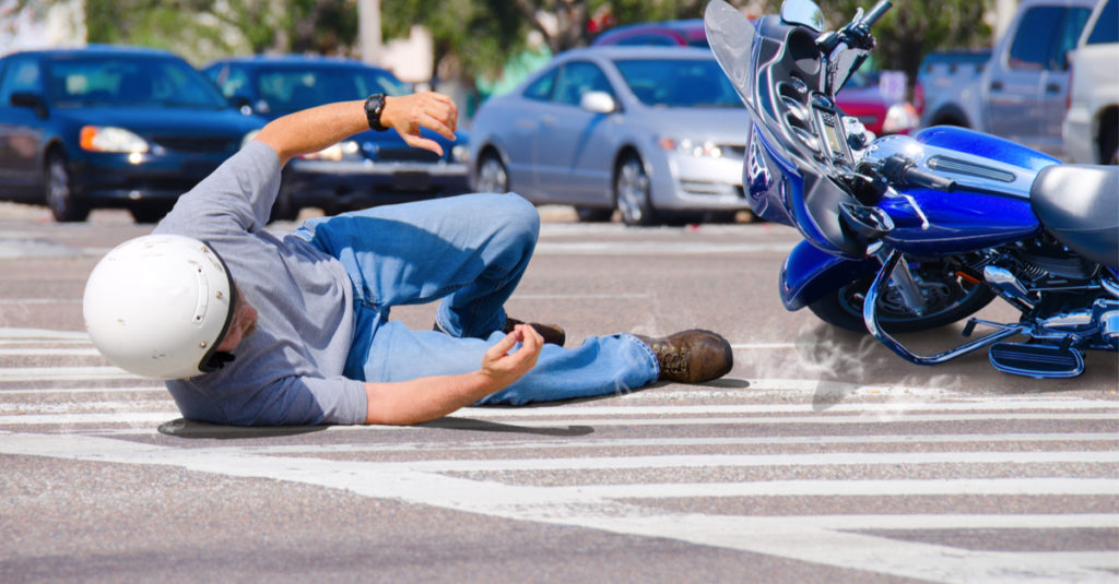motorcycle rider with road rash after falling on ground in motorcycle crash